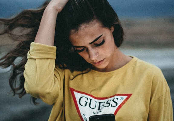 Γυναίκα φοράει κίτρινο φούτερ με λογότυπο Guess